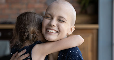 woman with bald head hugging child