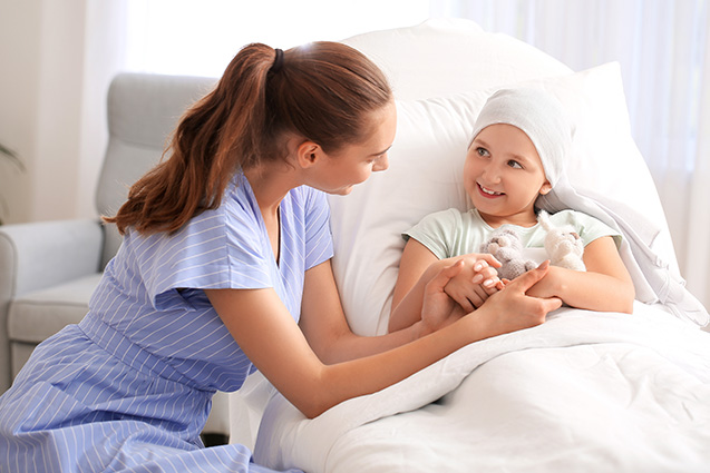 nurse interacts with smiling child cancer patient